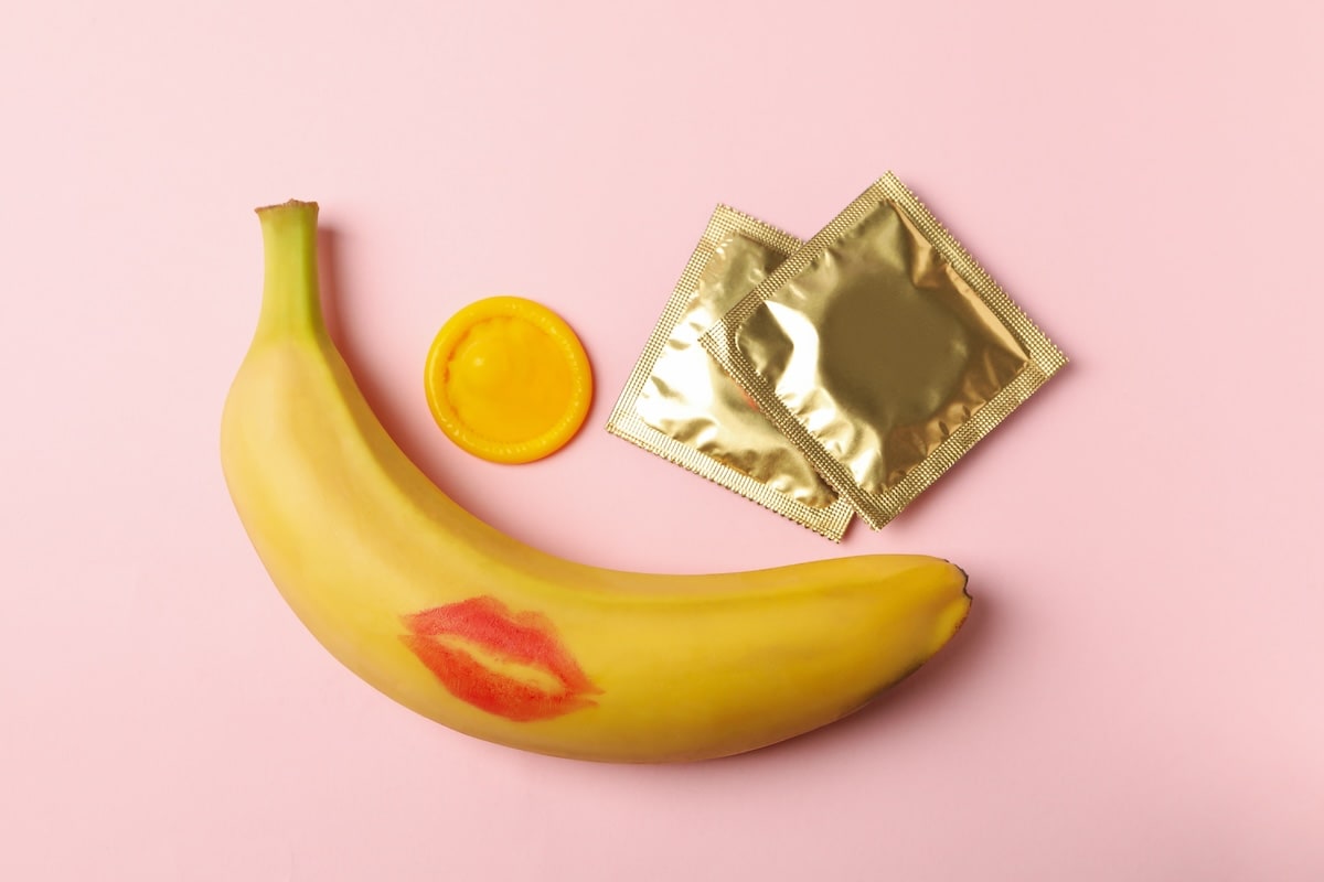 banana-with-lipstick-mark-and-condoms-on-pink-background